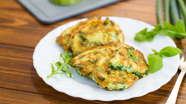 Close-up of two onion fritters on a plate with fresh herbs