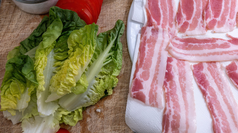 bacon grease being poured into a salad with lettuce, cheese, bacon