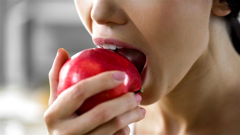Woman taking bite of red apple
