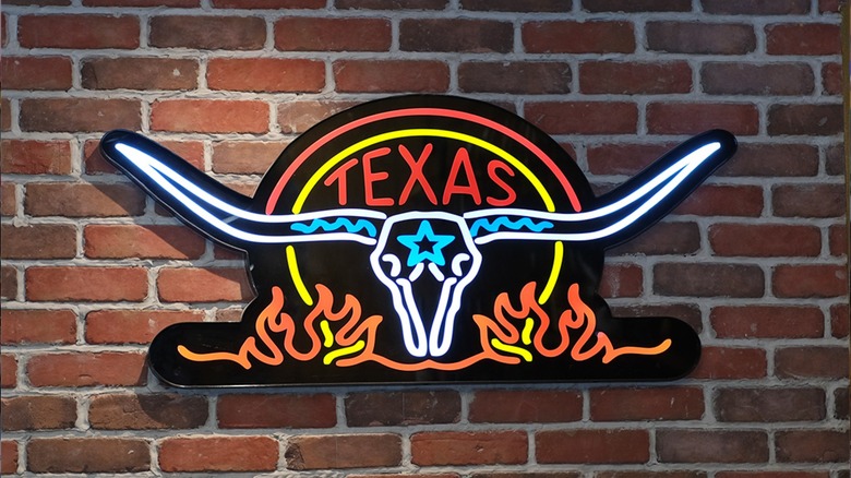 Neon Texas Roadhouse sign hanging on a brick wall at a Philippines location