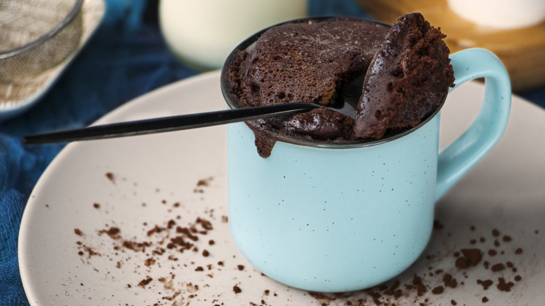 A spoon digging into a chocolate mug cake on a plate
