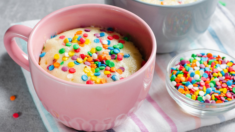 Funfetti mug cake topped with sprinkles in a pink mug