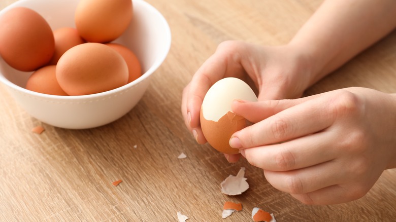 hands peeling hard boiled egg