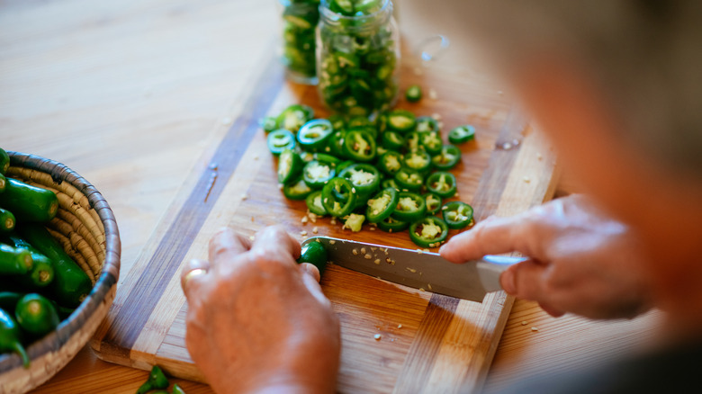 person cutting jalapeno peppers