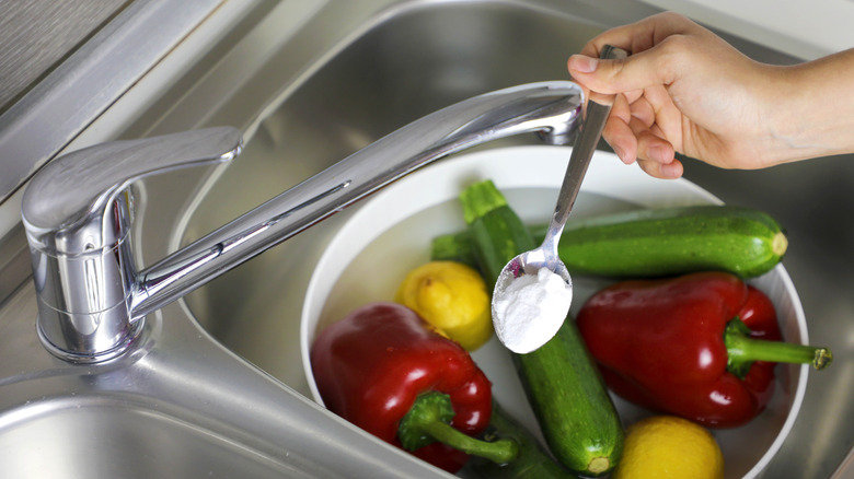 baking soda spoonful over sink of produce