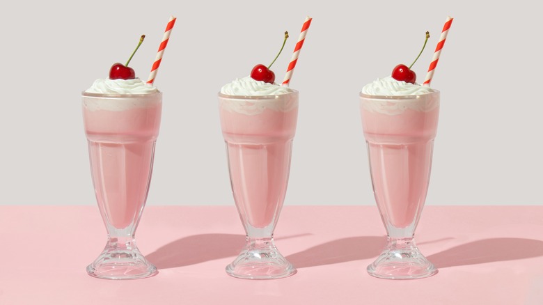 Three milkshakes on a pink background