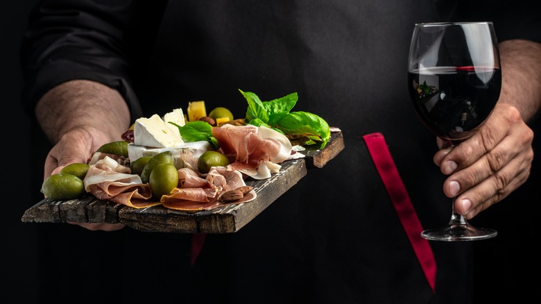Person holding serving board and wine