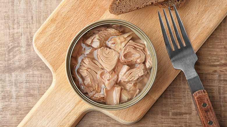 Opened tuna can on a wooden cutting board