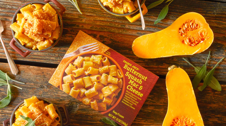 A package of Trader Joe's Butternut Squash Mac & Cheese surrounded by squash on a wood table