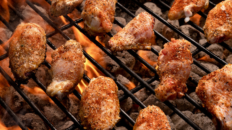 Seasoned chicken wings grilling over coals