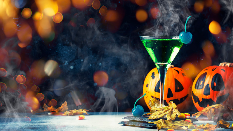 Green halloween cocktail with pumpkins and candy corn