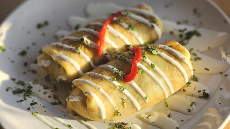 Plate with two small breakfast burritos with sour cream drizzle