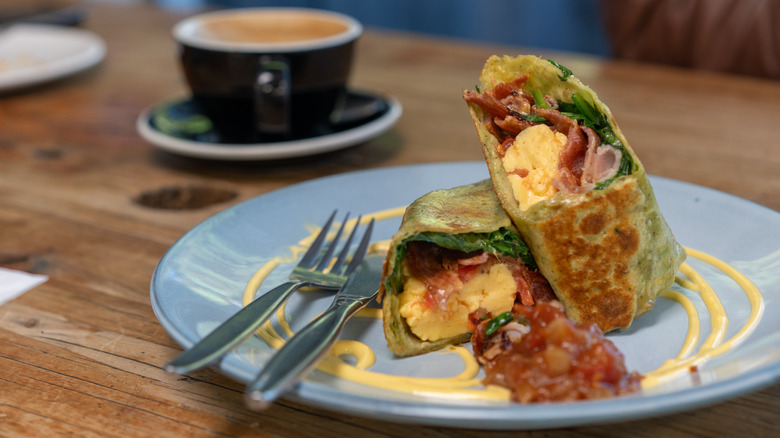 Breakfast burrito on a plate with coffee mug