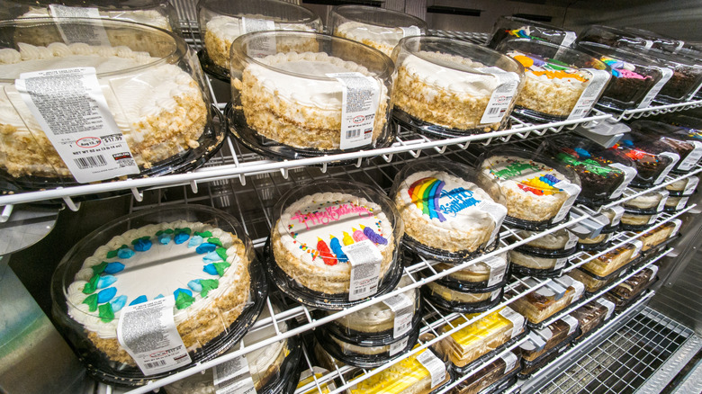 A metal shelf with a selection of plastic packages of cakes with decorations