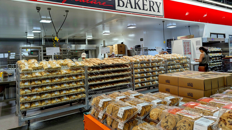 A woman stands in front of the Costco bakery looking at a package