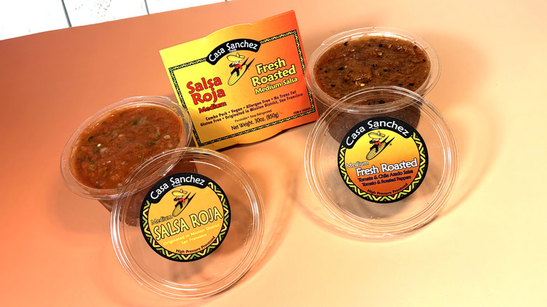 Two open containers of red salsa with their packaging