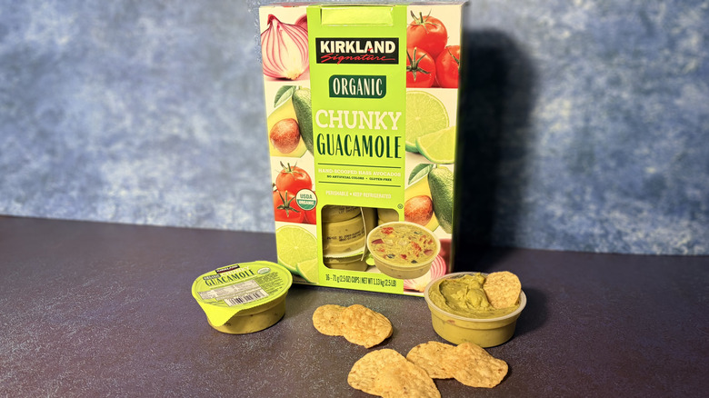 Small packages of Kirkland guacamole on a table with chips, next to the box