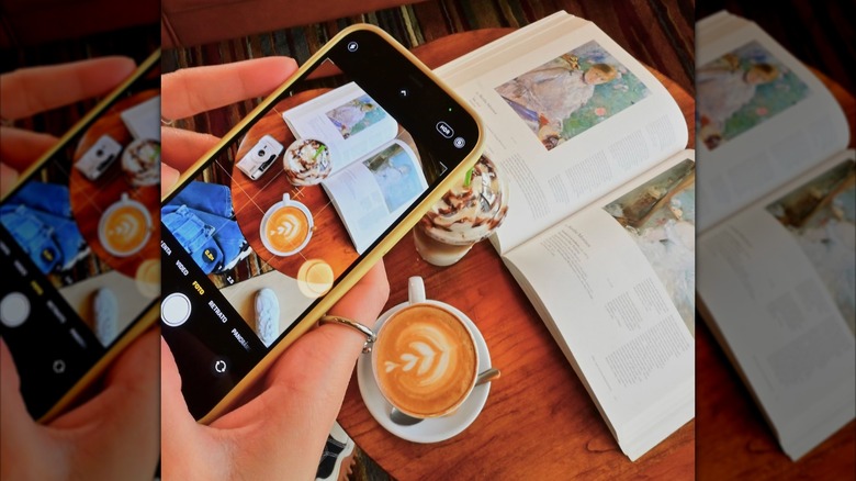 Phone taking photo of coffees and an open book