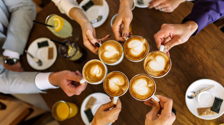 Friends lifting their lattes to cheers