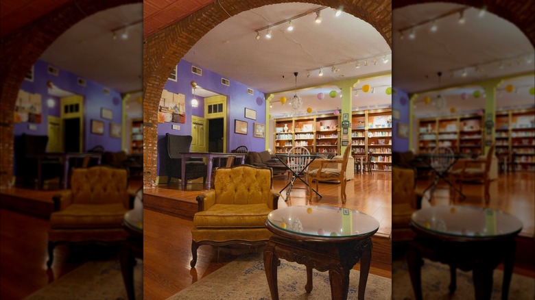 Bookshelves, velvet couches, and purple wall interior of Protagonist Cafe
