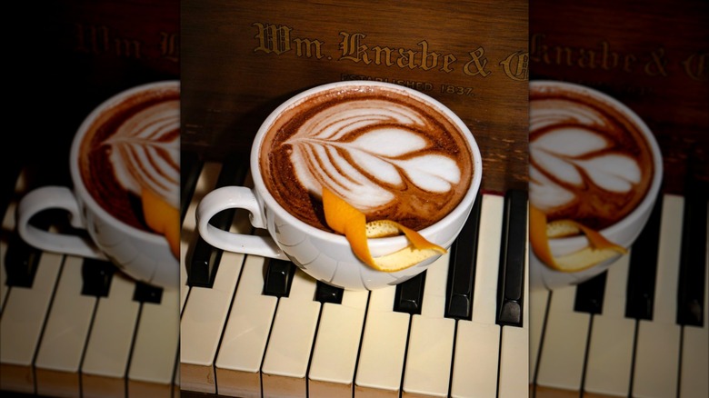 Latte with orange peel sat on top of piano keys