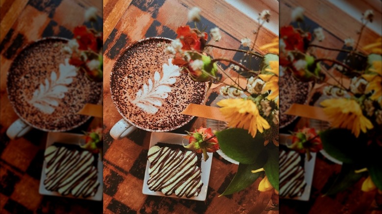 Mug with latte art and pastry photographed from bird eye view with floral arrangement