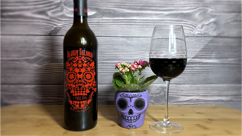 Bottle and glass of red wine with skull flowerpot decoration
