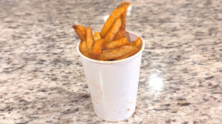Cup of cajun fries from Five Guys sitting in a cup on a kitchen counter.