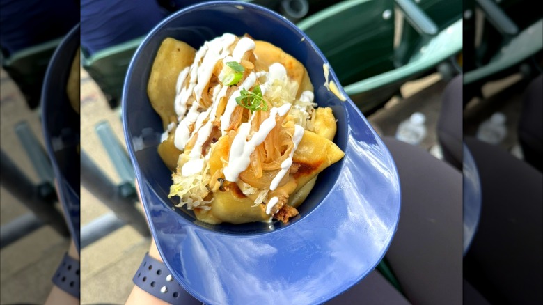 A fan holding a helmet filled with pierogi nachos