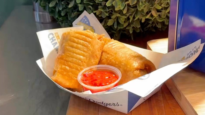 A deep fried chow mein chimichanga with spicy sauce on the side