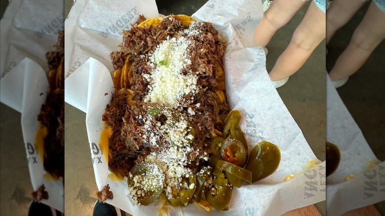 A tray of nachos topped with brisket, with cheese and jalapeños