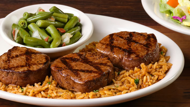 A plate of Texas Roadhouse Filet Medallions on a bed of rice with green beans