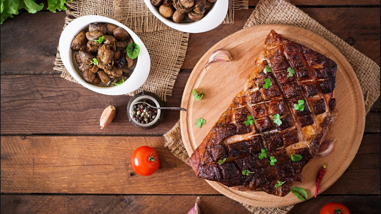 Tomatoes, mushrooms, and meat are arranged on a wooden surface
