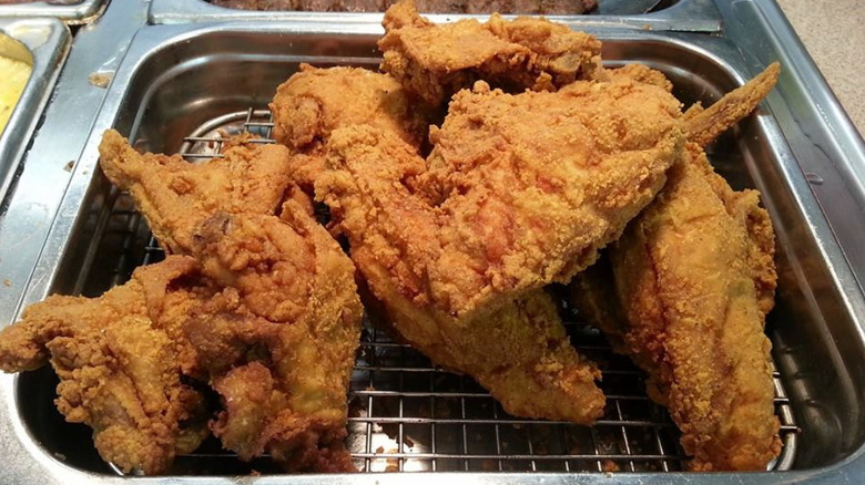 Fried chicken are piled on a metal grate