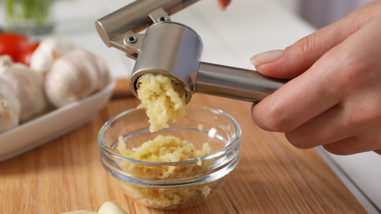 A person uses a garlic press