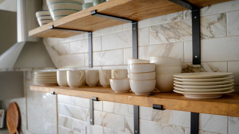 Open shelving in a modern kitchen, displaying cups, bowls, and plates