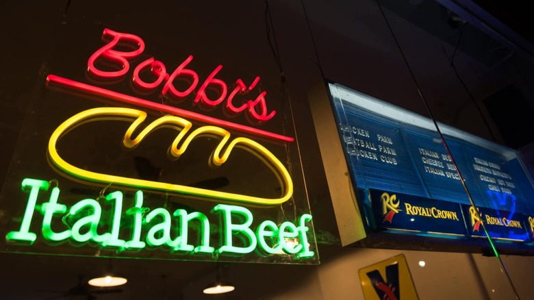 A neon sign reading "Bobbi's Italian Beef" next to a menu board