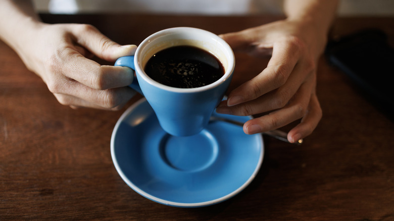 Person holding a cup of coffee in a blue mug