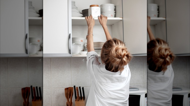 Woman with bun reaching for top shelf