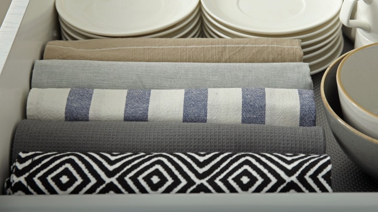 rolled linens in a drawer beside saucers