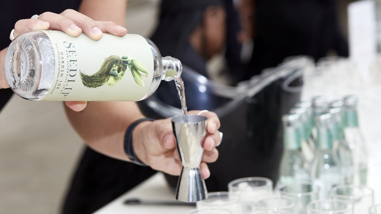 Hand pouring Seedlip into measure