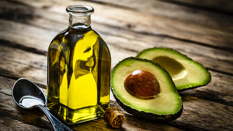 bottle of avocado oil next to halved avocado
