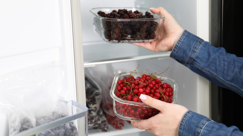 A person pulling glass containers of berries out of the fridge