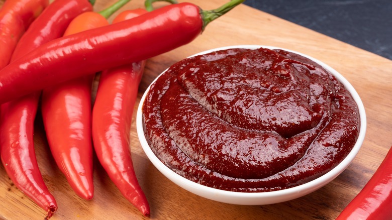 Gochujang next to red chili peppers 
