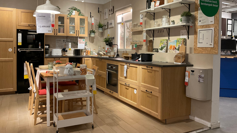 An IKEA kitchen with light wood cabinets and a table in the center.