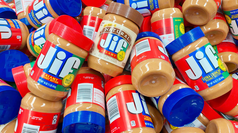 Many tubs of Jif Creamy, Natural, and Extra Crunch, in a grocery store bin