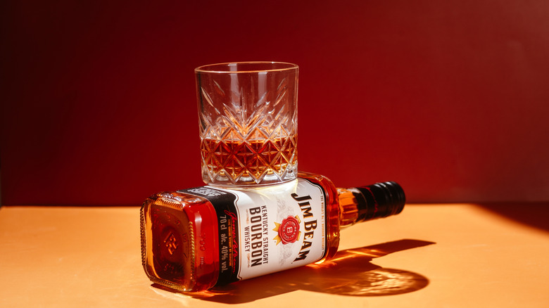 Láhev whisky Jim Beam na žlutém pozadí