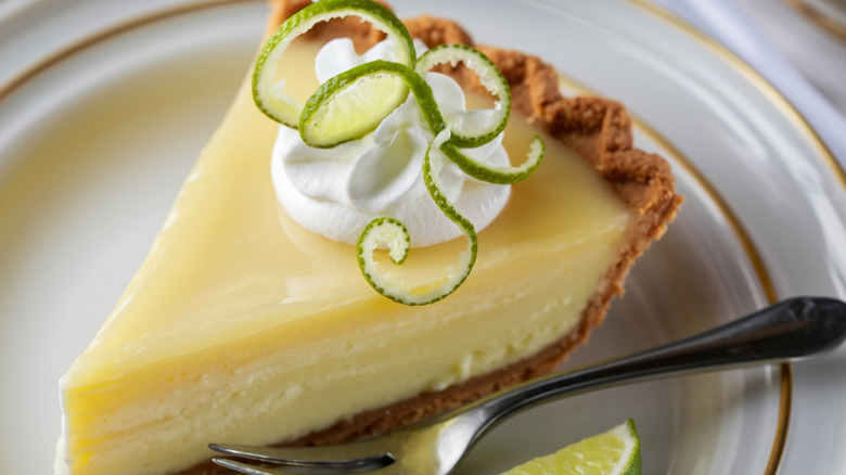 A slice of key lime pie with a spiralized lime peel on top
