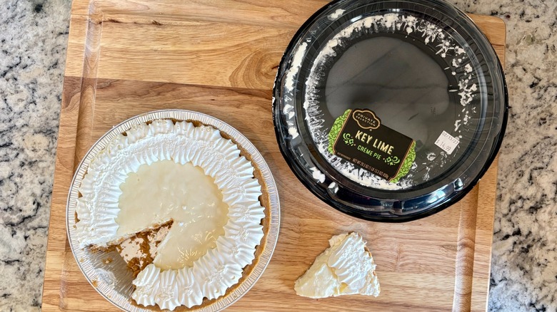 A Private Selection Key Lime Creme Pie out of its packaging and set aside, with 1 slice removed
