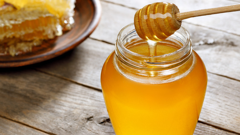 Jar of honey with honeycomb in the background